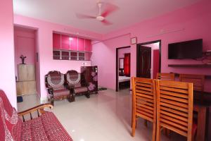 古鲁瓦尤尔2 BHK Furnished Flat - 200 m to Guruvayur Temple - For FAMILIES ONLY的一间带粉红色墙壁的客厅和一间餐厅