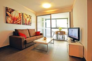 奥里韦拉海滩迪曼特蓝色公寓式酒店的带沙发、电视和桌子的客厅