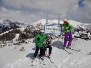 巴德小基希海姆Bio Naturhof Ottingerhof的三人滑雪,站在山上的一个标志旁