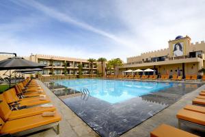 马拉喀什马拉喀什亚当公园酒店及水疗中心的一座设有黄色椅子的酒店游泳池,一座建筑
