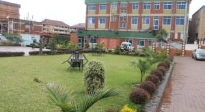 坎帕拉Pearl Highway Hotel Kibuye Kampala的一座有建筑的院子和一座种植了植物的草坪