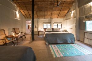 奇旺Tiger Tops Tharu Lodge的一间卧室配有两张床和一张桌子及椅子