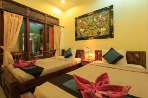 乌布KT夸雅斯民宿酒店的一间卧室设有两张床和窗户。