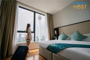 吉隆坡Pavilion Ceylon Hill Suites, Bukit Bintang的站在酒店房间,望向窗外的女人