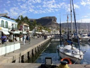 莫甘海滩Precioso Yate en el centro del Puerto de Mogan的码头,码头上设有船只,人们在码头上行走