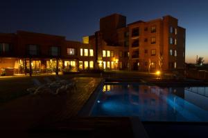 蒙得维的亚Regency Park Hotel的游泳池,晚上有椅子和建筑