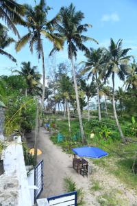 阿勒皮Shoreline Marari Beach Villa At Golden Beach Mararikulam的棕榈树海滩上的野餐桌椅