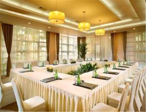 东莞东莞峰景高尔夫酒店 的大房间设有长桌和白色椅子