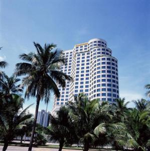 海口Hainan Junhua Haiyi Hotel的一座高大的建筑,前面有棕榈树