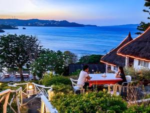 长滩岛Boracay Water World Hotel的坐在桌子旁看海洋的男人和女人