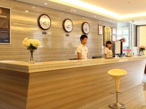 北京169 Business Hotel的两人站在餐厅柜台边,餐厅有时钟