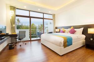 Thinadhoo马尔代夫羽毛旅馆的配有一张床、一张书桌和一扇窗户的酒店客房
