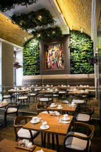 布达佩斯布达佩斯威望酒店的餐厅墙上挂有桌椅和植物