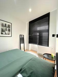 布鲁塞尔Cosy apartment in Brussels的一间卧室配有一张床和一个带黑色百叶窗的窗户。