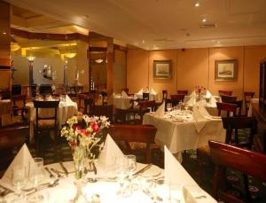 特拉利Brandon Hotel Conference & Leisure Centre的餐厅设有餐桌、白色桌布和鲜花