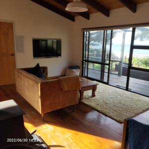 Parapara Beachfront Bliss - Your Parapara Seaside Retreat的带沙发和大窗户的客厅