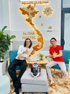 胡志明市ALOHA SAIGON HOSTEL by Local Travel Experts - Newly opened, Less-touristy location, Spacious rooms, Glass shower bathroom, Free breakfast, Quiet alley and Cultural exploration的坐在桌子旁的男人和女人,戴头盔