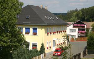 TrogenHotel "Alte Schule" Trogen的一座黄色的房子,前面有一辆红色的汽车