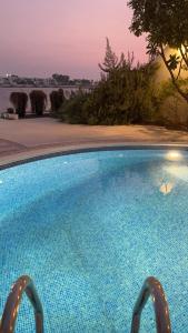 Durrat Al BahrainDurrat Bahrain villa for rent的一座蓝色的大型游泳池,背面是日落