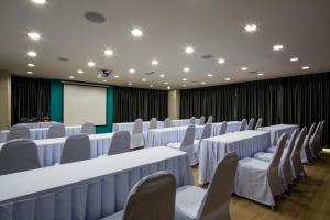 曼谷曼谷叻抛利沃特尔酒店的一间会议室,配有白色的桌椅和屏幕
