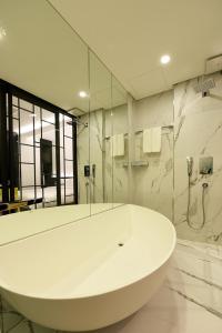 首尔因菲尼酒店的白色的浴室设有浴缸和淋浴。