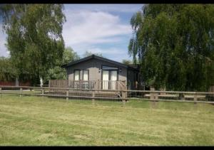 BrooklandPuddledock - luxury lodge - Romney Marsh, Kent的一座带门廊和围栏的小房子