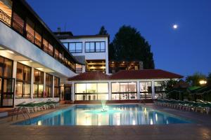 阿格罗斯罗登度假酒店的一座游泳池,在晚上在建筑物前