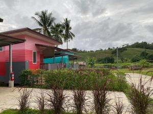 Ban Huai Ya-uS&P Huayau Resort น้ำอ้อย的一座粉红色的房子,前面有一棵棕榈树