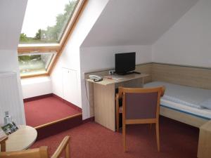 SewekowSeehotel Ichlim的小房间设有一张床和一张带电脑的书桌