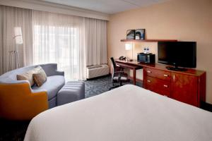 温莎Courtyard By Marriott Hartford Windsor Airport的酒店客房配有一张床和一张书桌及一台电视