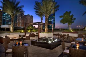迪拜阿塔纳酒店的一个带桌椅的屋顶露台,棕榈树