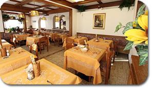 坎皮泰洛迪法萨Hotel Primula的一间带木桌的餐厅和一间用餐室