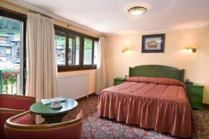 马萨纳胡特兰酒店及Spa的一间卧室配有一张带红色床罩和桌子的床。