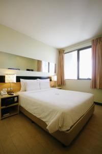 伊洛伊洛伊洛伊洛启航酒店的卧室配有一张白色大床和两个窗户
