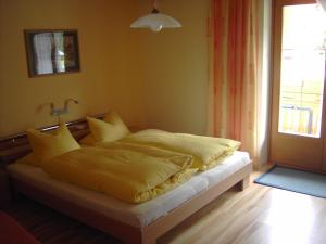 德弗雷根谷地圣雅各布古特温格豪斯酒店的一间卧室配有一张带黄色床单的床和一扇窗户。