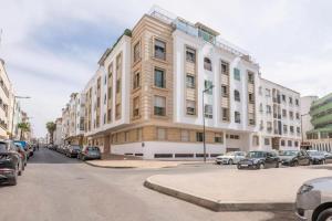 拉巴特Appartement Rabat Agdal City Centre - SwiftStay的一条城市街道上一座大型建筑,有停放的汽车