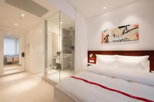 维也纳红宝石玛丽维也纳酒店的卧室配有一张白色大床和一个玻璃步入式淋浴间。