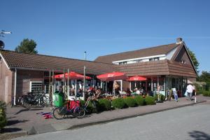 WolphaartsdijkCamping 't Veerse Meer的一座建筑前面有红伞和自行车