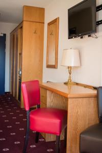 莱森阿尔卑斯经典酒店的配有书桌和红色椅子的房间