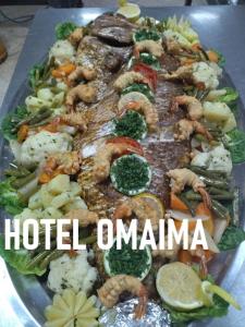 阿尤恩Hotel OMAIMA的一大盘海鲜和蔬菜,上面写着酒店的“omana”字样