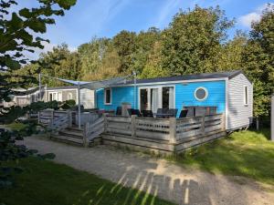 KropswoldeCozy Tiny SolHouse 7 - Near Groningen - 5 Star Location的蓝色和白色的小房子,设有木甲板