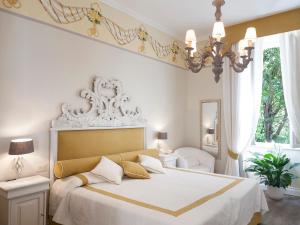 马里纳迪马萨马雷蒙帝别墅酒店的一间卧室配有一张带白色床单和吊灯的大床