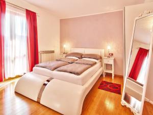 罗维尼科维克公寓的白色卧室设有两张床和红色窗帘