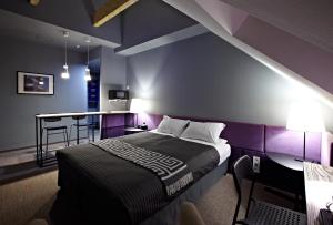 第聂伯罗纽波特酒店的一间卧室设有紫色的墙壁和一张带桌子的床