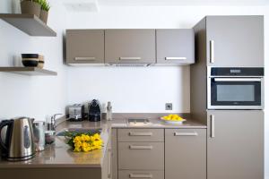 伦敦The Rosebery by Supercity Aparthotels的厨房配有白色家电和黄花,位于柜台上