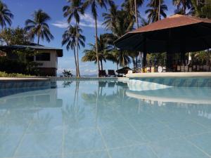 圣维森特Sunset Beach Resort by RF at SanVicentePalawan OPC的一个带遮阳伞和棕榈树的游泳池