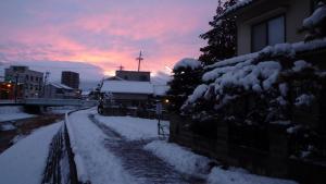 松本松本背包客旅馆的一条雪覆盖的街道,在后面有日落