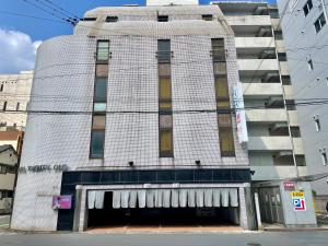 Morimachiホテル21長崎的一座高大的白色建筑,前面有一个车库