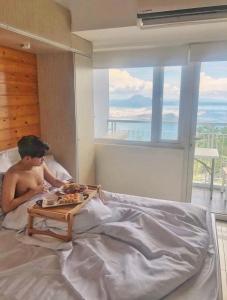 大雅台JT Tagaytay Suites的躺在床上吃一盘食物的人