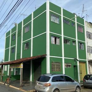 巴西利亚Hostel da 18的一座绿色建筑,前面有停车位